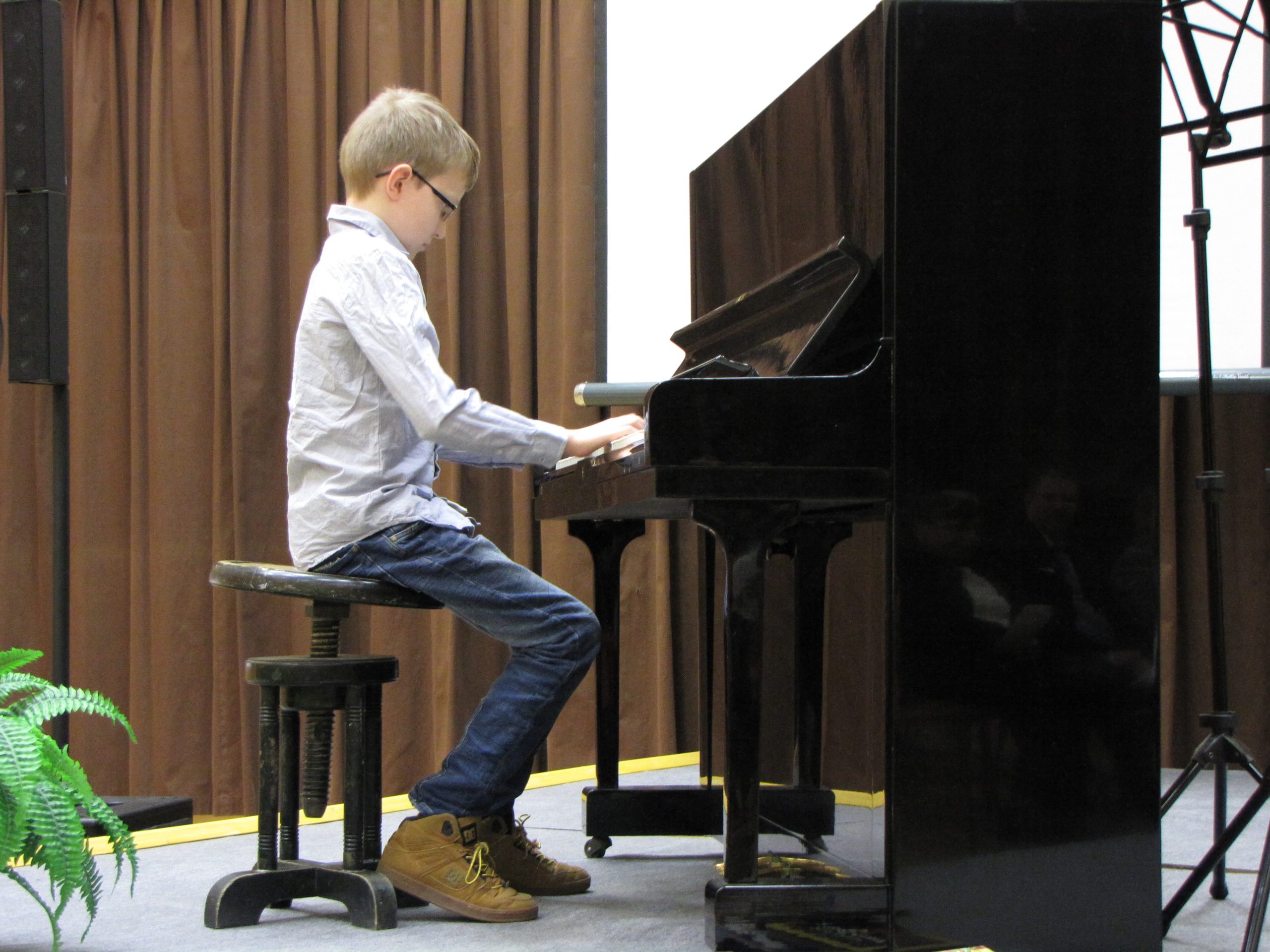 Toinen silmälasipäinen poika esittää pianonsoittoa.