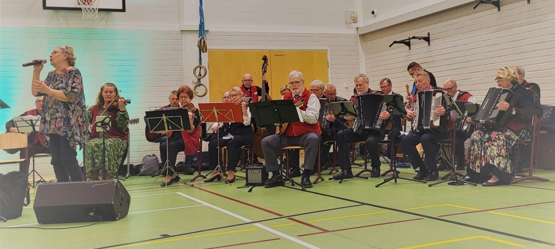 Nainen laulaa mikrofoniin, pelimannit soittavat taustalla.
