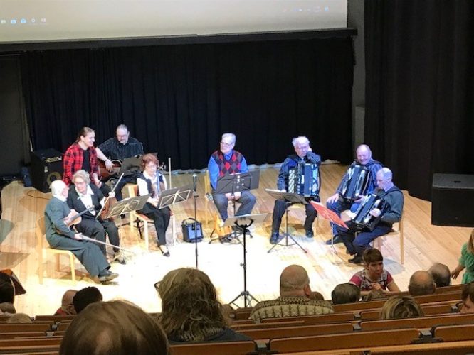 Miehiä ja naisia eri instrumentteineen istumassa ennen soiton alkua.