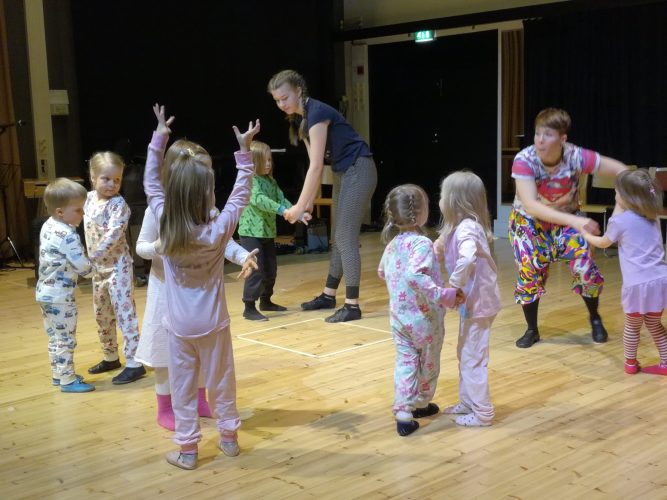 Kahdeksan pikkulasta pyjamissaan tanssii pareittain ohjaajineen.