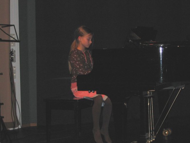 Tyttö esiintymislavalla soittamassa pianoa.