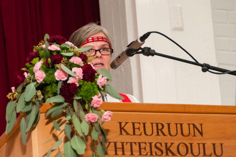 Kansallispukuun pukeutunut lautakunnan puheenjohtaja pitämässä puhetta puhujapöntössä.